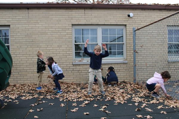 Preschool kids play in leaves on the playground